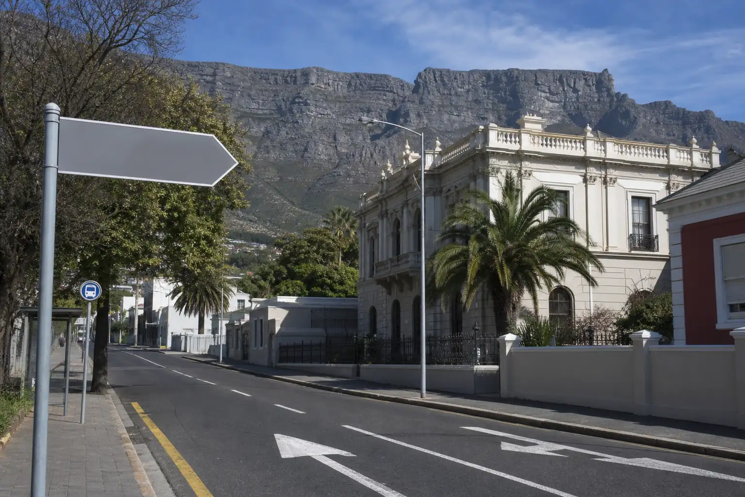 Public street scene showing architecture, road markings, transit sign, and mountain clues for place identification